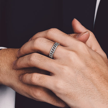A close-up of a person wearing a silver chain-link ring on one finger. 