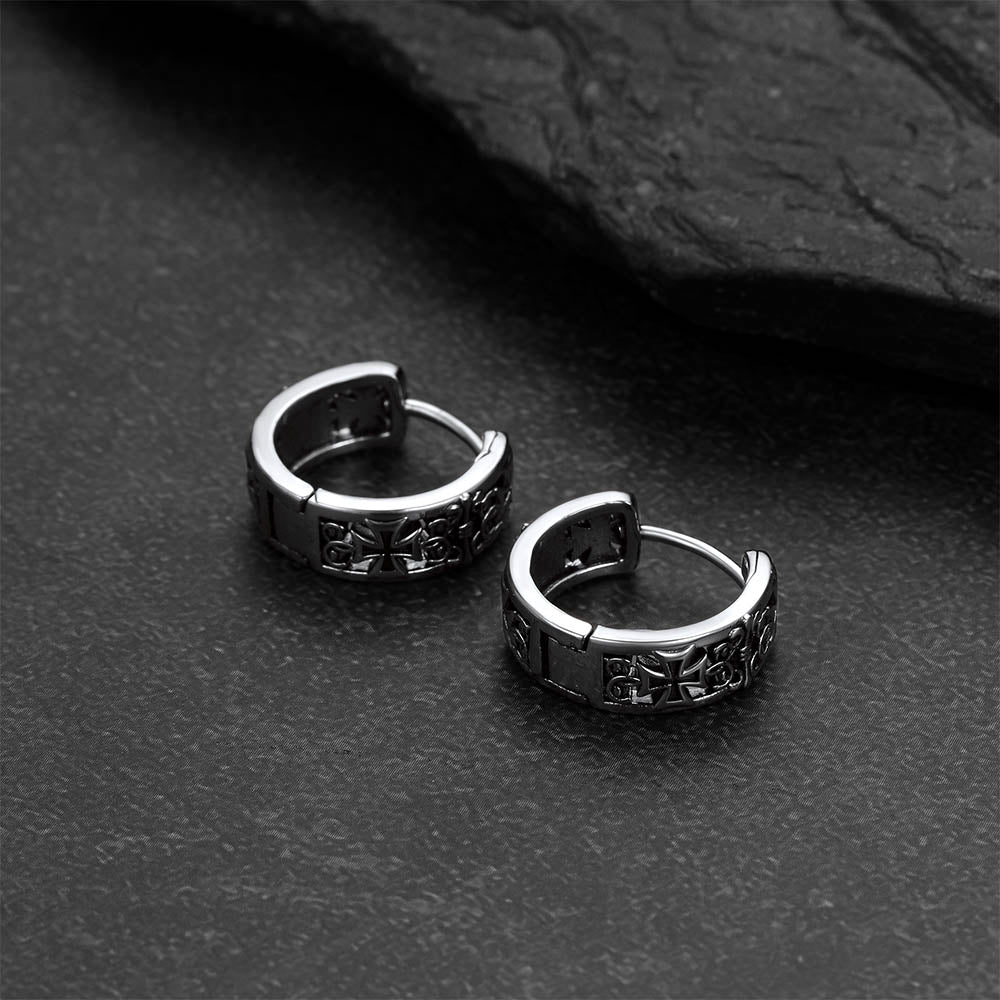 Pair of silver hoop earrings on a dark textured surface