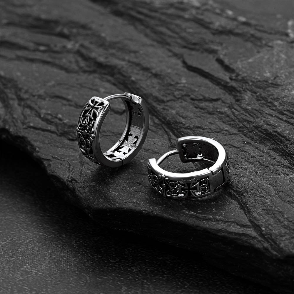 Pair of silver hoop earrings on a dark stone surface