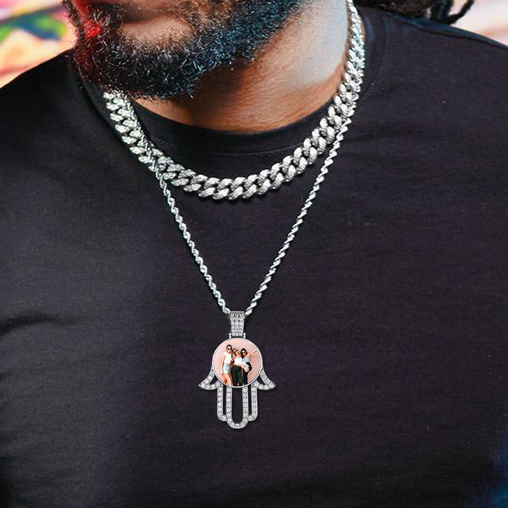 Person wearing a silver necklace with a Hamsa hand pendant featuring a family photo.