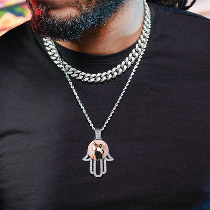 Person wearing a silver necklace with a Hamsa hand pendant featuring a family photo.