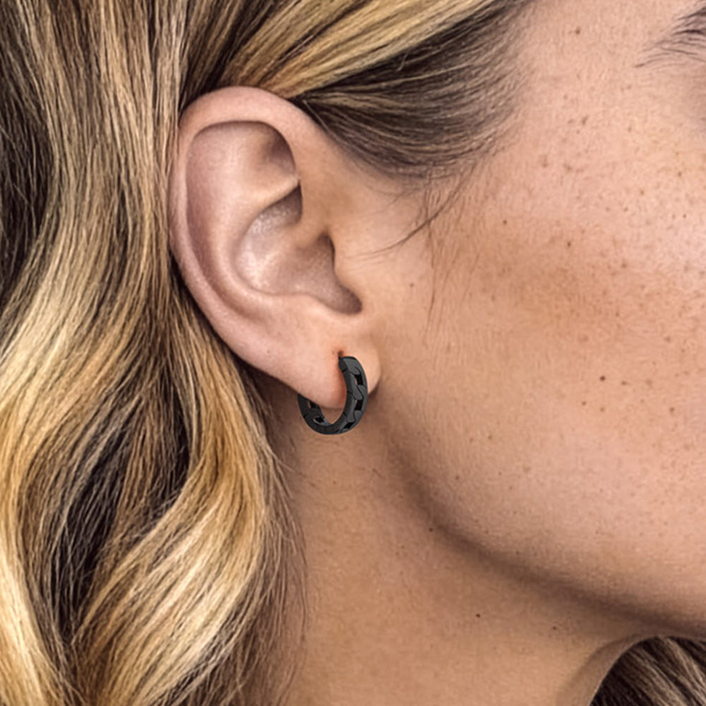 Close-up of a person wearing a black hoop earring with blonde hair.