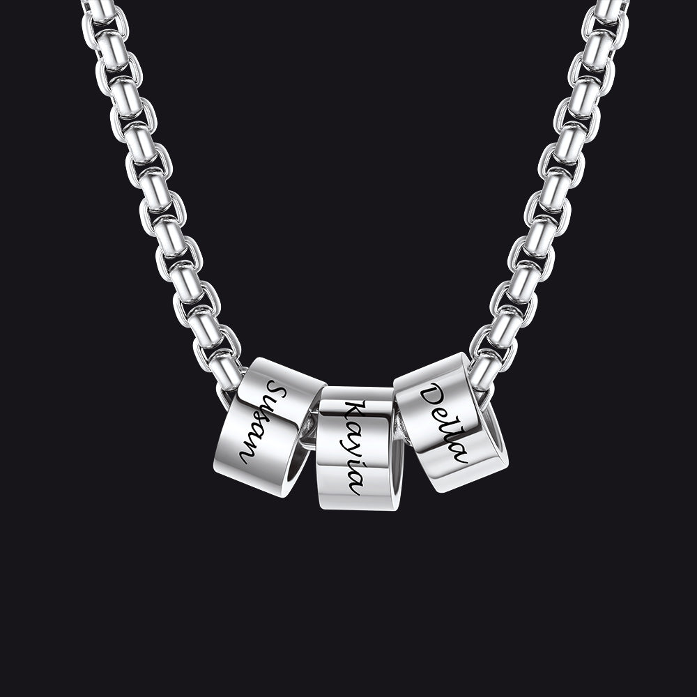Silver necklace with three engraved cylindrical pendants on a black background