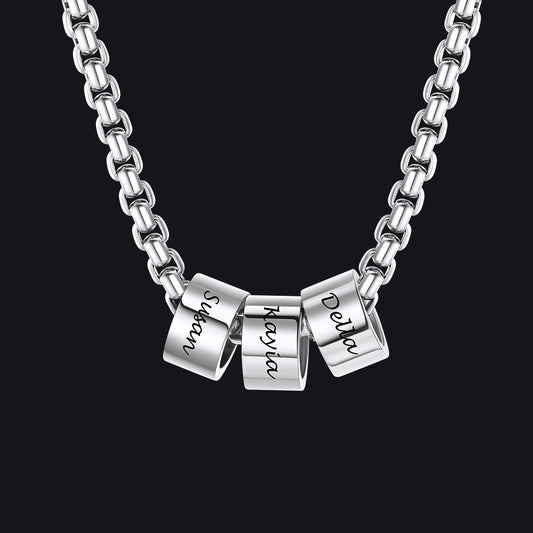 Silver necklace with three engraved cylindrical pendants on a black backgroundimg