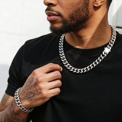Man wearing a silver cuban chain necklace and bracelet against a white background