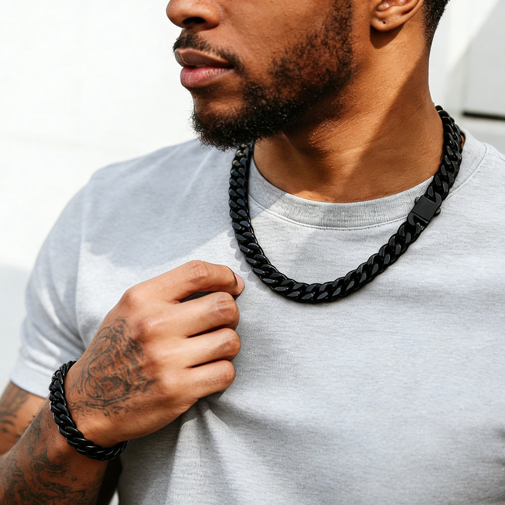 Man wearing a black chain necklace and bracelet on a white background