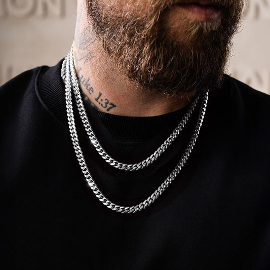 Man wearing two silver chain necklace with a black shirt, close-up on neck and chest.img