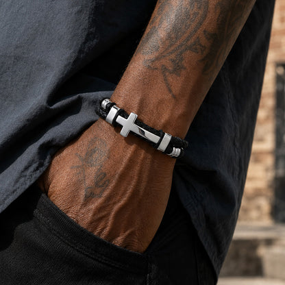 Man wearing black braided silver-tone cross leather bracelet on wrist