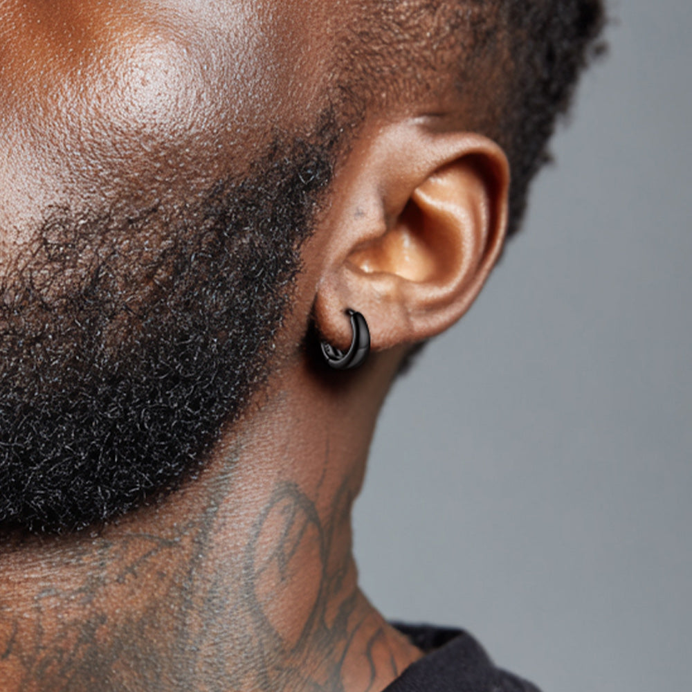Close-up of a man's ear with a black hoop earring against a gray background