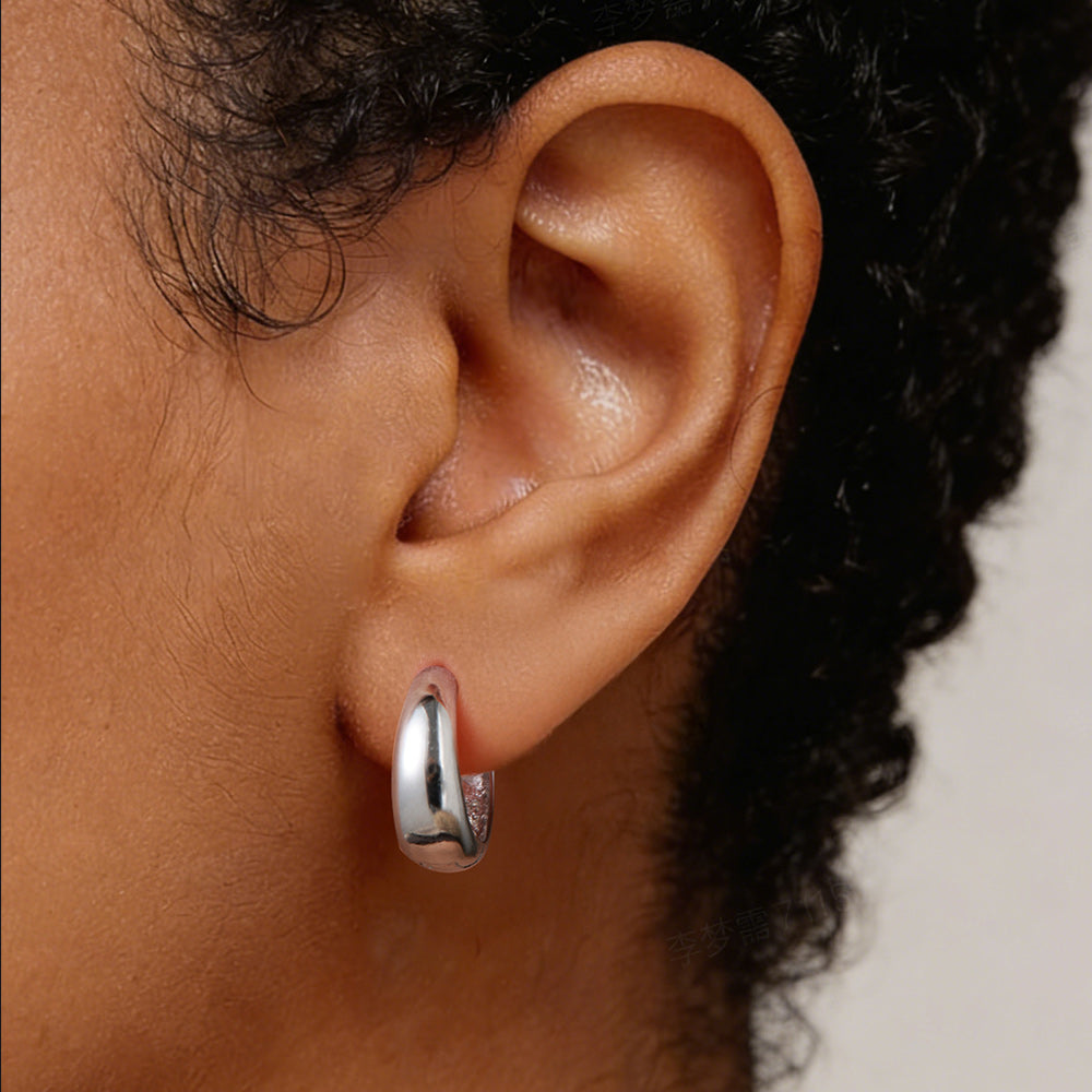 Close-up of an ear wearing a silver hoop earring with blurred background