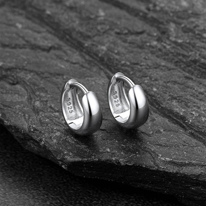 Pair of silver hoop earrings on a dark stone surface