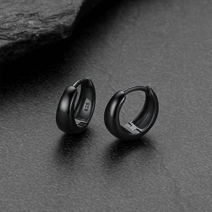 Black hoop earrings on a dark textured surface