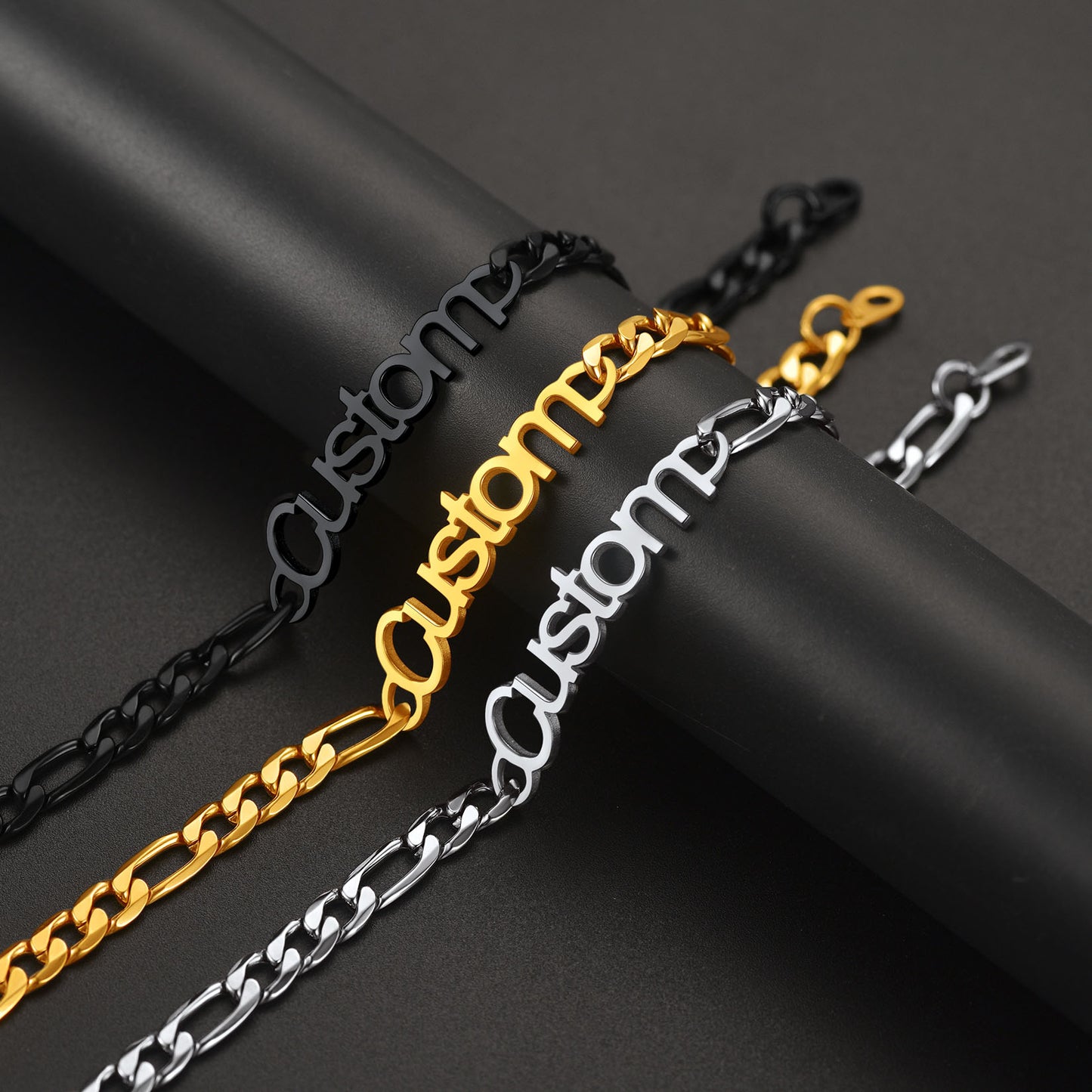 Three customizable chain necklaces in black, gold, and silver on a dark background.