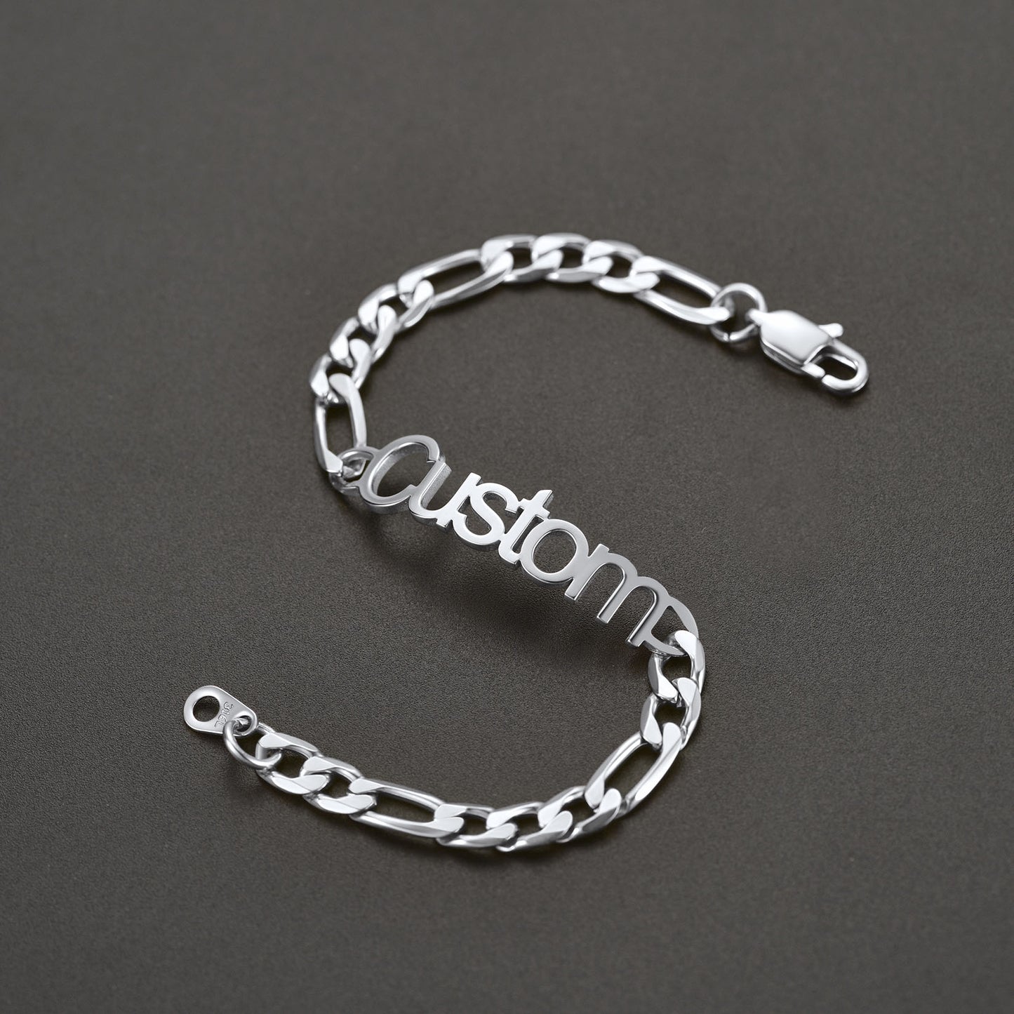 Silver chain bracelet with 'Custom' engraving on a dark gray background