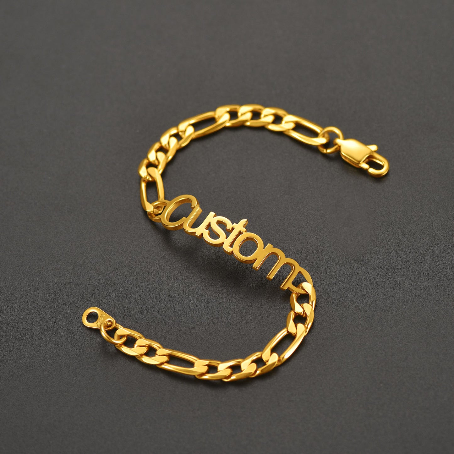 Gold chain bracelet with 'custom' engraving on a dark gray background
