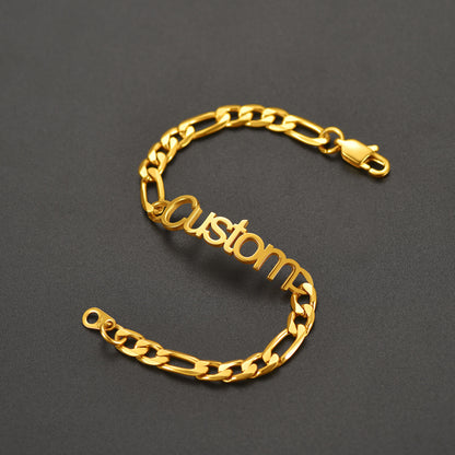 Gold chain bracelet with 'custom' engraving on a dark gray background