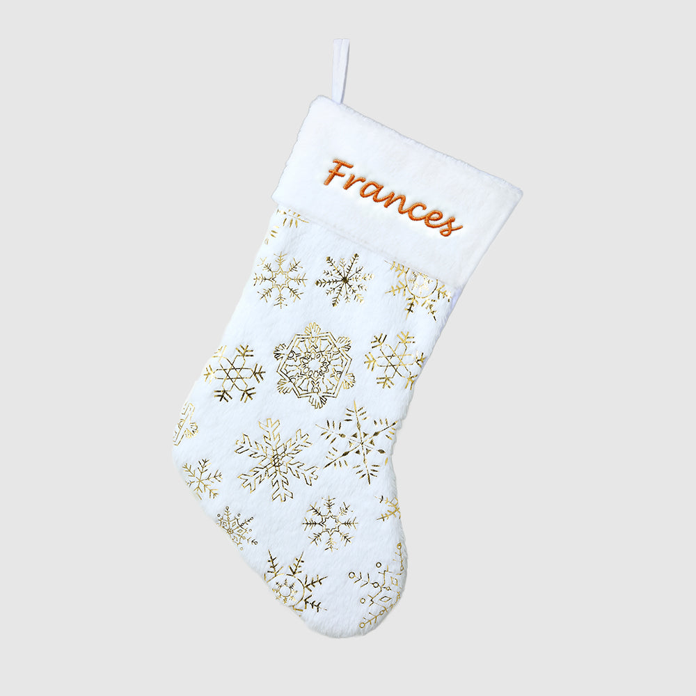 White Christmas stocking with gold snowflake patterns and 'Frances' embroidered on a light gray background