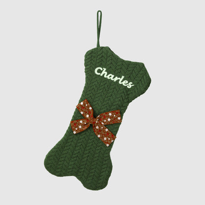Green knitted Christmas stocking with a red bow and 'Charles' embroidered on a light gray background