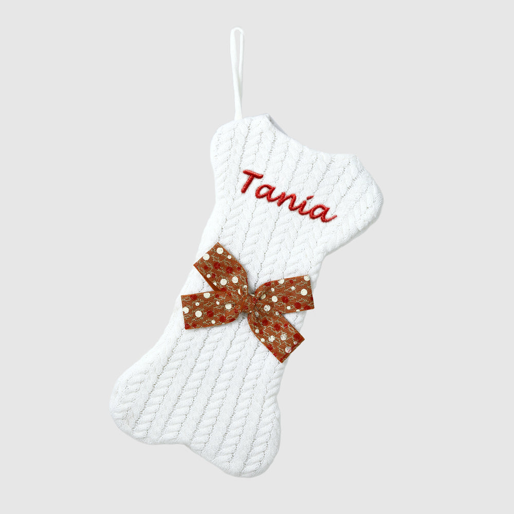 White textured Christmas stocking with a red sequin bow and 'Tania' embroidered on a light gray background