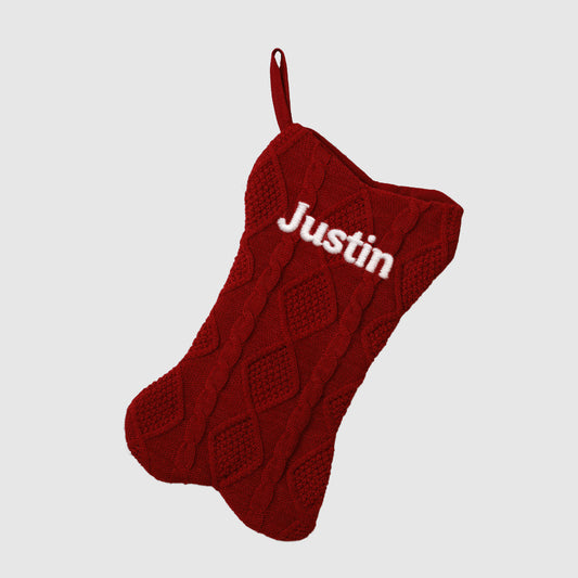 Red knitted stocking with 'Justin' embroidered on a light gray backgroundimg
