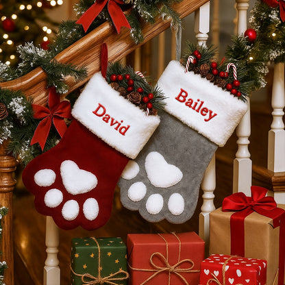 Two Christmas stockings with paw prints and names 'David' and 'Bailey', surrounded by presents and a decorated staircase.