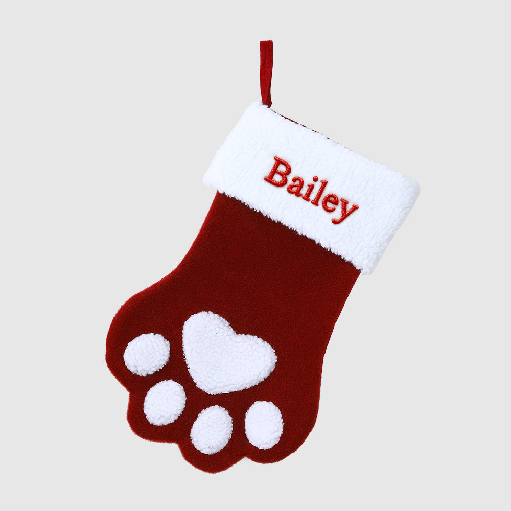 Red Christmas stocking with white paw print and 'Bailey' embroidered on a beige background