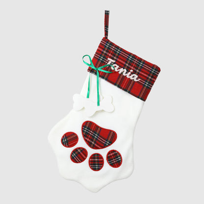 White dog muzzle with red plaid paw prints and a red plaid Christmas stocking with 'Tania' on a white background.