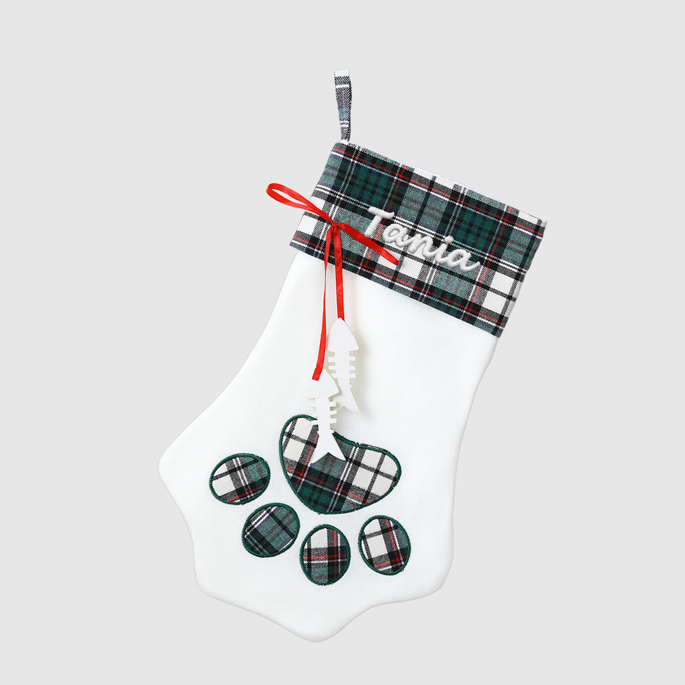 White Christmas stocking with plaid accents and paw print design on a light gray background