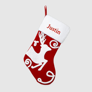 Red Christmas stocking with white reindeer design and 'Justin' text