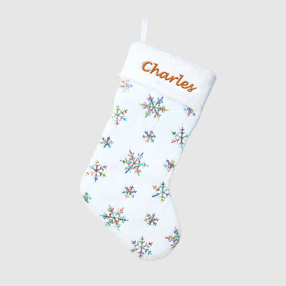 White Christmas stocking with colorful snowflake patterns and embroidered name 'Charles' on a light gray background.