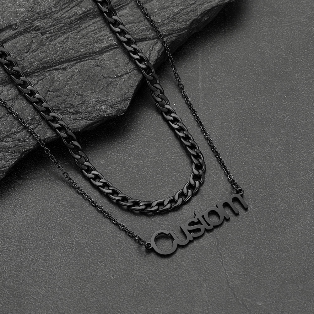 Black chain necklace with 'Custom' pendant on a dark stone surface