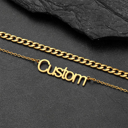 Gold chain necklace with 'Custom' pendant on a dark stone surface