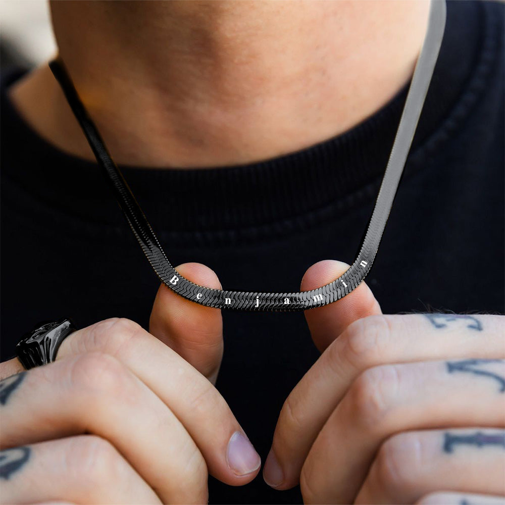Person holding a black snake chain necklace