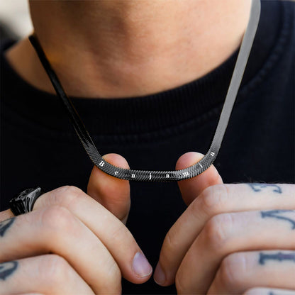 Person holding a black snake chain necklace