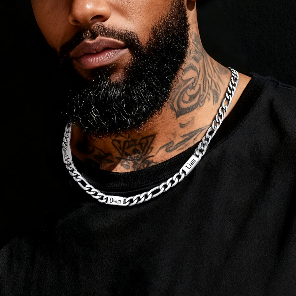 Man wearing a silver chain necklace with tattoos on his neck against a black background
