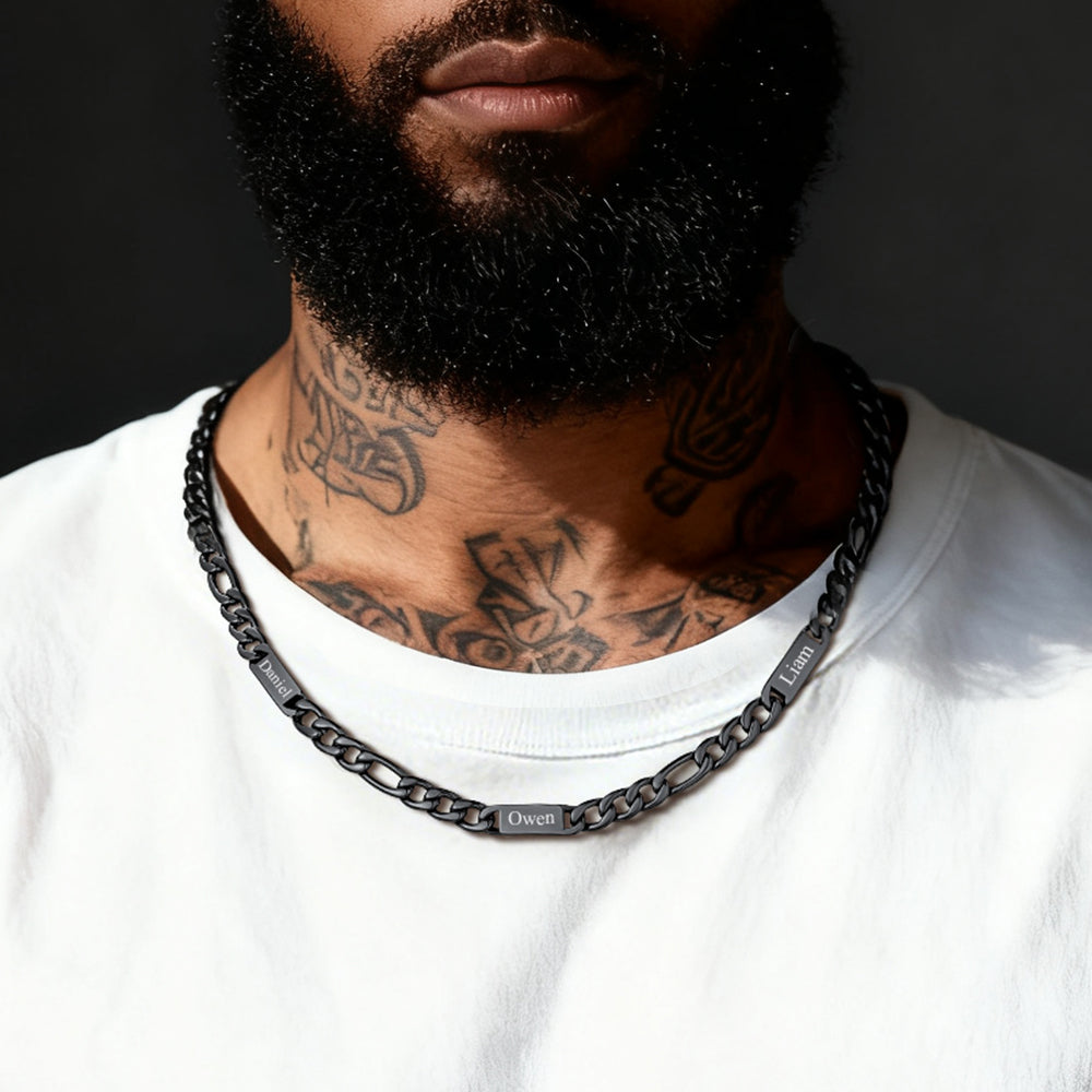 A man wearing a black chain name necklace with a dark background