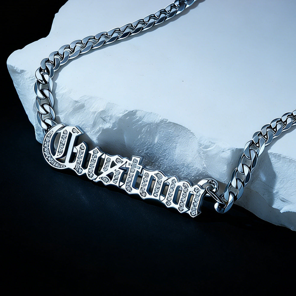 Silver chain necklace with 'Custom' engraving on a stone surface