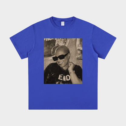 Blue t-shirt with a graphic of a person wearing sunglasses and a cap on a white background