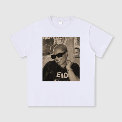 White t-shirt with a printed photo of a person wearing sunglasses and a cap on a light gray background