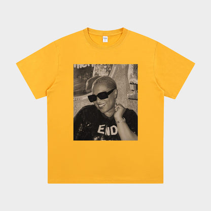 Yellow t-shirt with a graphic of a person wearing sunglasses and a cap on a white background