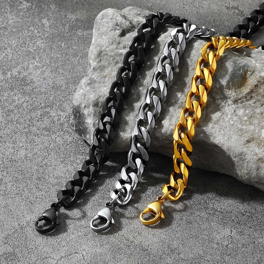 Three chain dog collars in black, silver, and gold on a stone surface.