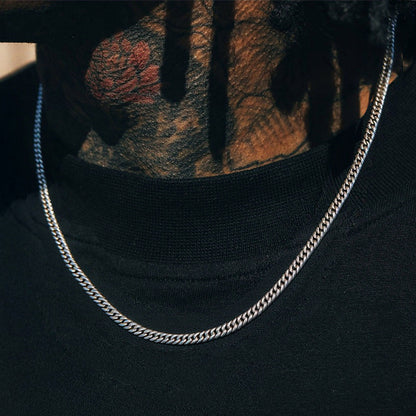 Silver chain necklace on a black shirt with tattooed arm