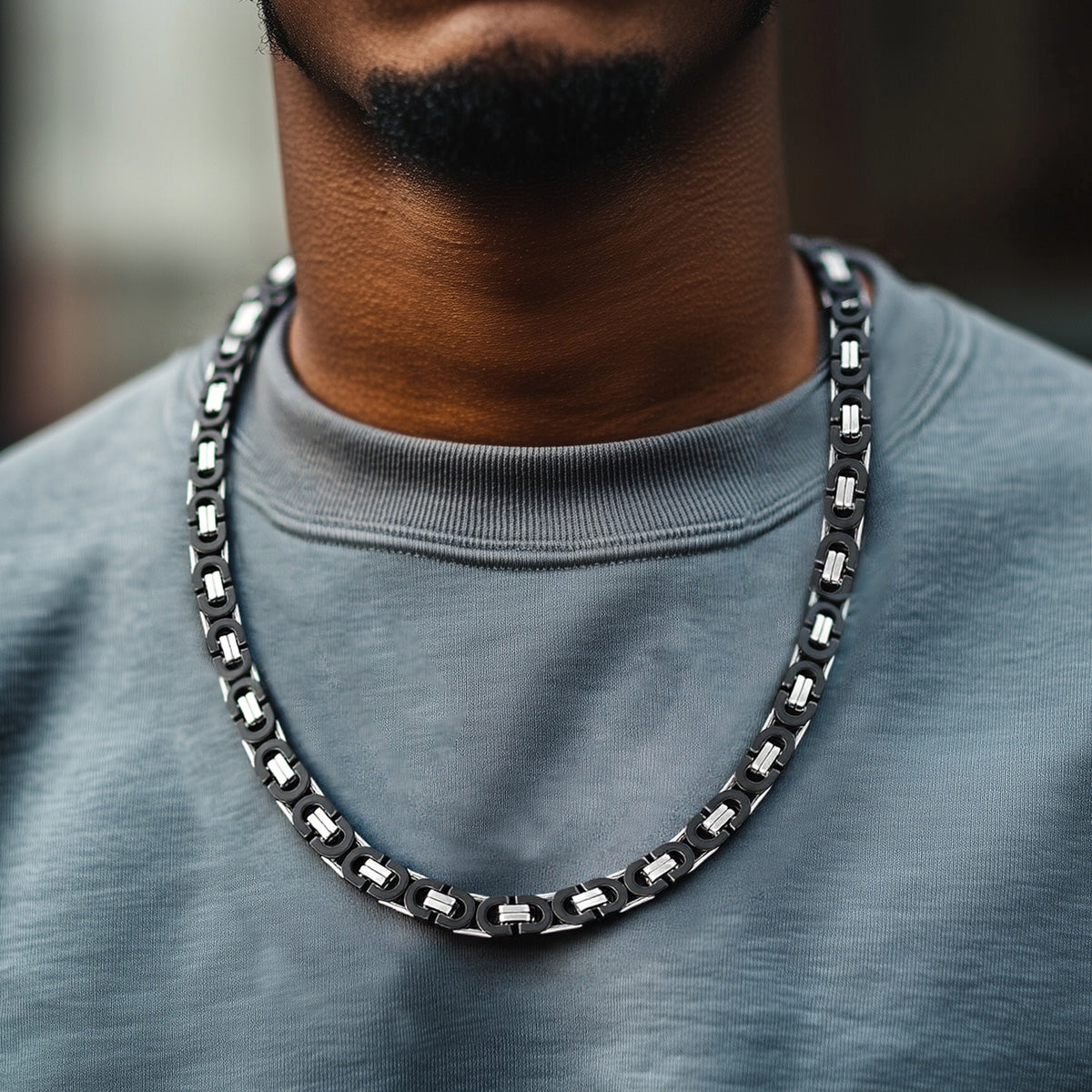 Person wearing a black chain necklace with a blurred background