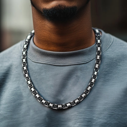 Person wearing a black chain necklace with a blurred background