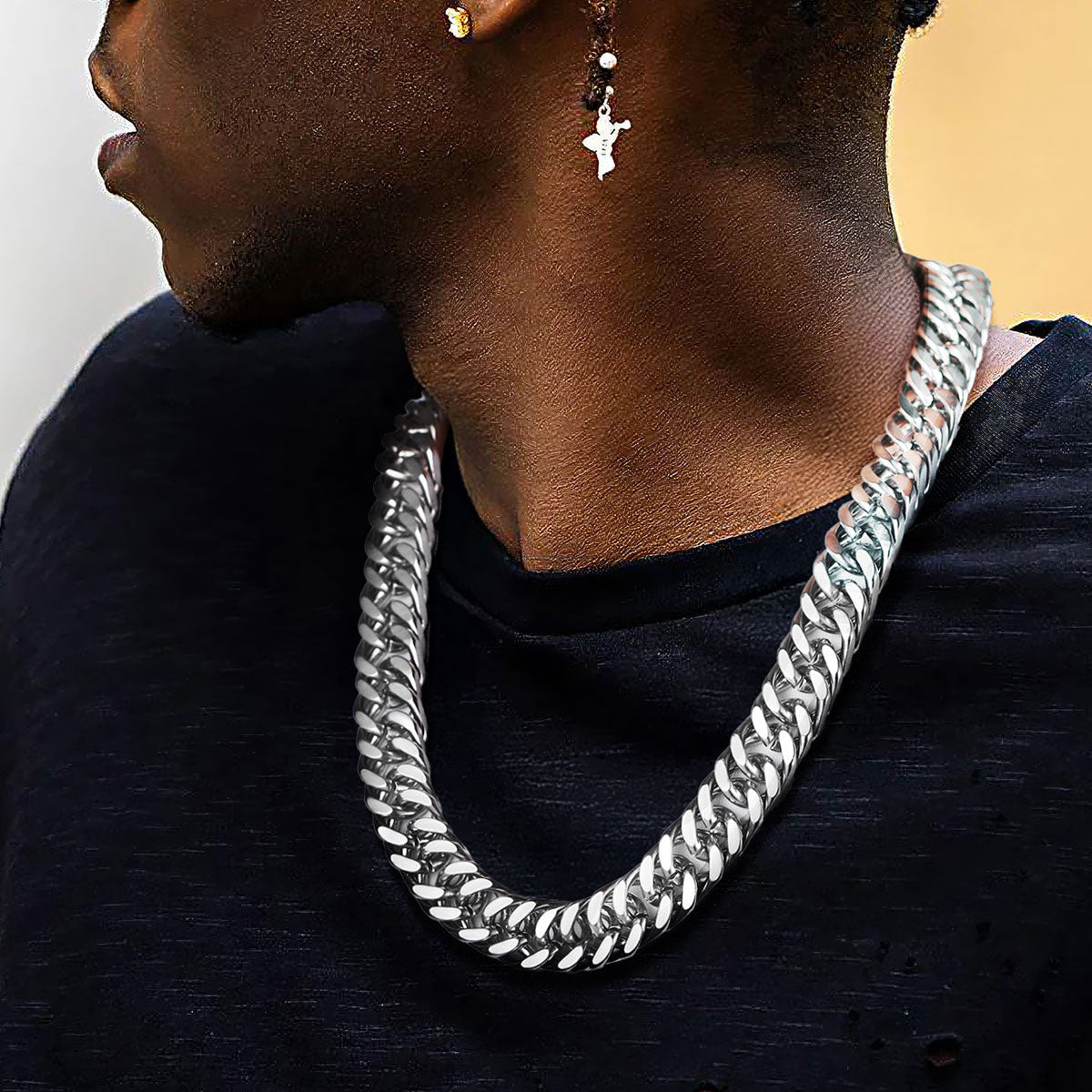 Person wearing a silver cuban chain necklace with a neutral background