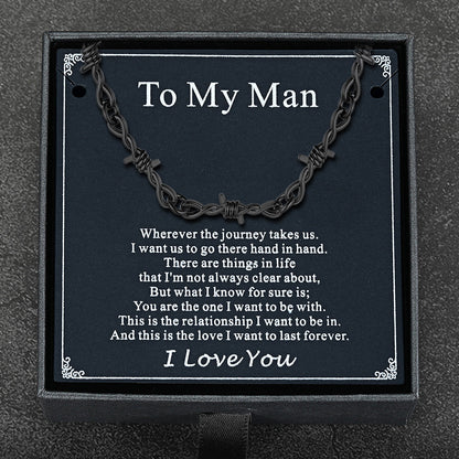 Flat lay of barbed wire chain with gift packaging and punk-themed card