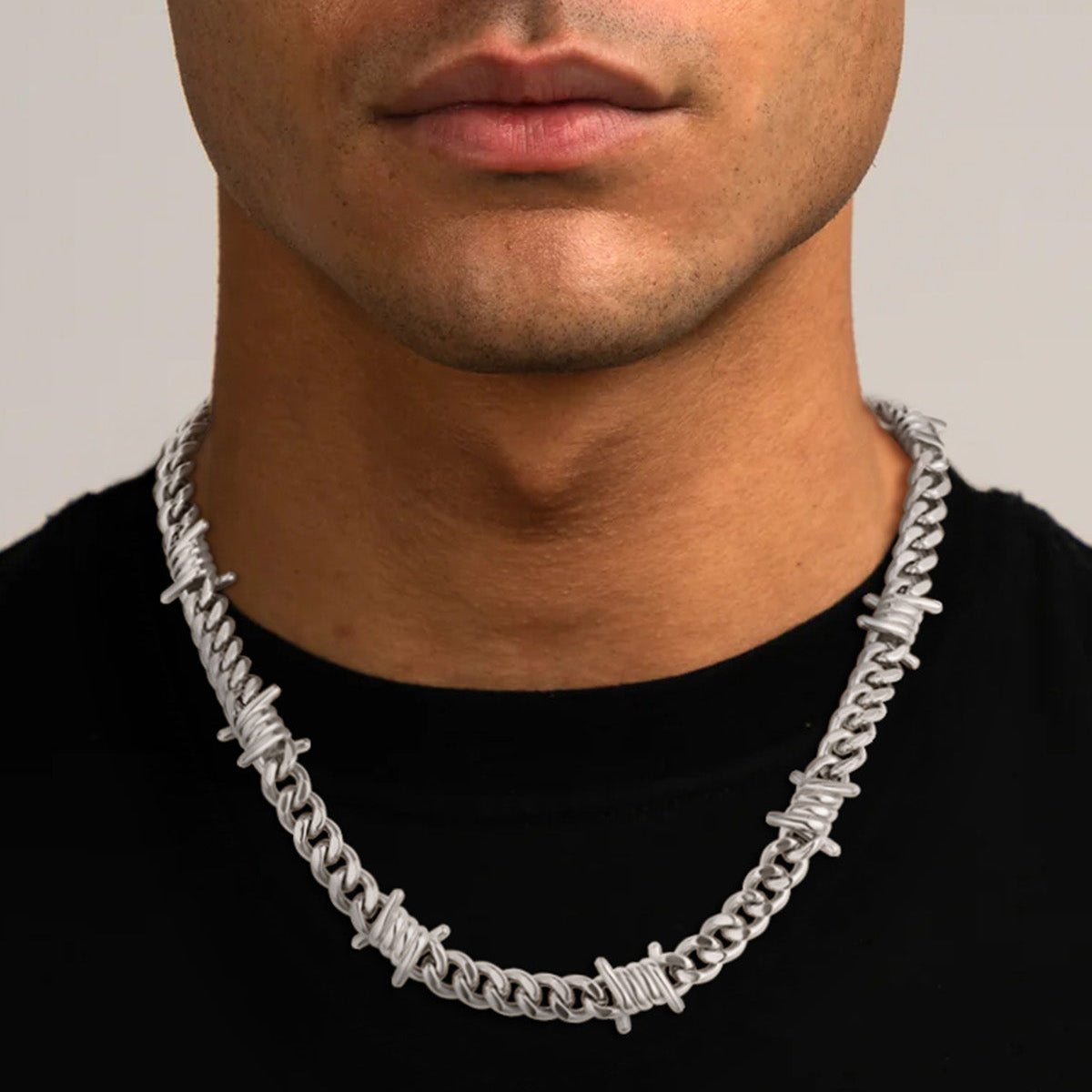 Man wearing a silver chain necklace against a neutral background