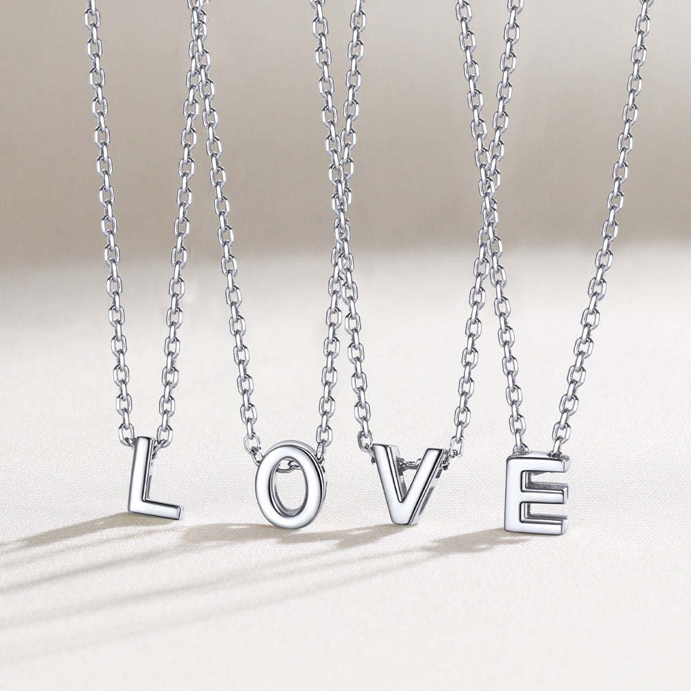 Silver necklaces spelling 'LOVE' on a light background