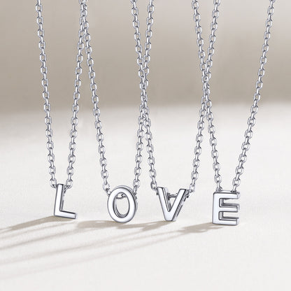 Silver necklaces spelling 'LOVE' on a light background