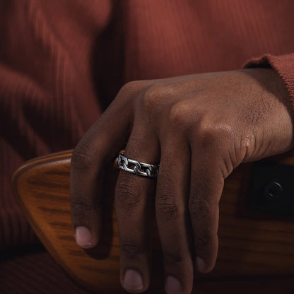 Hand wearing a silver ring on a brown background